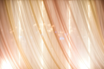 Soft translucent beige and pink curtains with glowing bokeh lights in the background, symbolizing elegance and romantic celebration