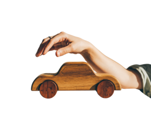 A hand holds a small brown wooden toy car with visible wheels against a plain white background in a studio shot