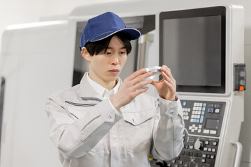 工場で旋盤加工品・フライス加工品を確認する男性作業員