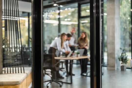 Businessmen blur in the workplace in office with computer or shallow depth of focus of abstract background, view from glass wall