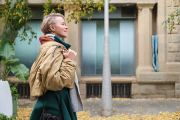 Fototapeta premium side view of Adult woman enjoying autumn city street lifestyle in barcelona
