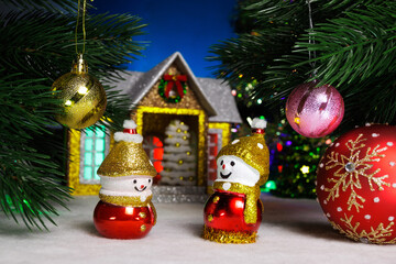Between two balls on Christmas tree branches there are snowmen with a large ball against the background of a house