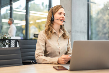 Portrait of happy smiling female customer support phone operator at workplace.