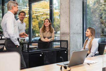 Happy four business people executive team working at laptop having discussion at office meeting showing financial project