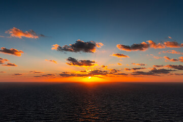 Malta sunset landscape. Dramatic sunset over the horizon of the Mediterranean Sea at Dingli Cliffs in Malta, with deep orange and red colors reflecting on the water under a dark cloudy sky. Sea sunset