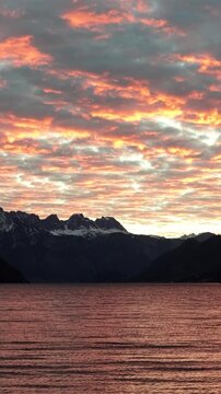 Vertical sunset clouds over Walensee lake with alpine mountain skyline