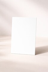 Naklejka premium Vertical greeting card mockup on soft beige background with shadow overlay and blank white front cover