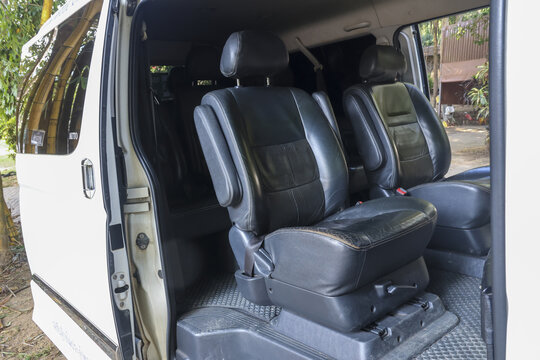 Inside of luxury white passenger van with open door showing comfortable black leather seat and interior waiting for traveler looking elegant and expensive for vip transport service