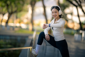 Fototapeta premium Asian woman stretching checking smartwatch in park