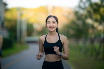 Fototapeta premium Asian woman jogging in park enjoying healthy lifestyle