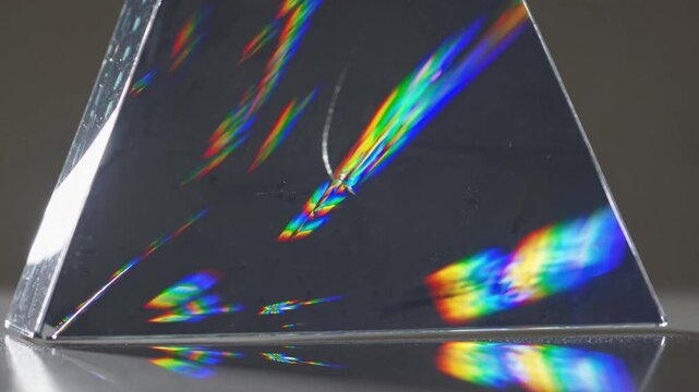 Reflective surface illustrates colorful light dispersions in laboratory setting, Minimalist studio employs prism to demonstrate slow shimmering light refractions and rainbow reflections