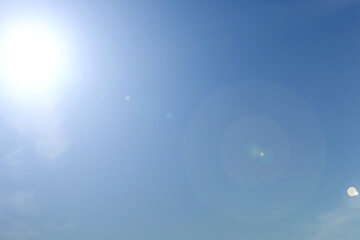 Bright blue sky background with sunlight and lens flare, copy space