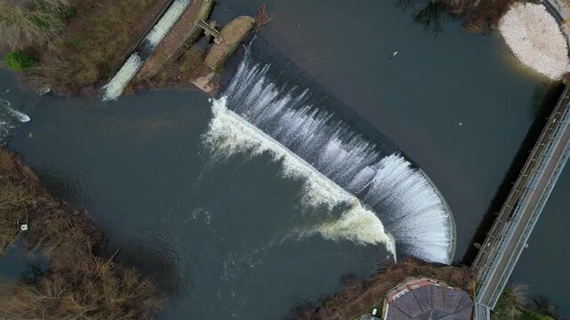 Aerial view of the weir on the River Derwent with its cascading water and adjacent buildings and bridge, Derby, England, United Kingdom.