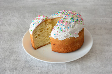 Traditional Easter Kulich Cake with Icing and Colorful Sprinkles on white plate