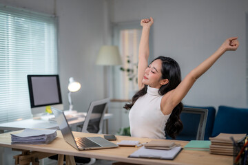 Asian businesswoman stretching arms while working from home office
