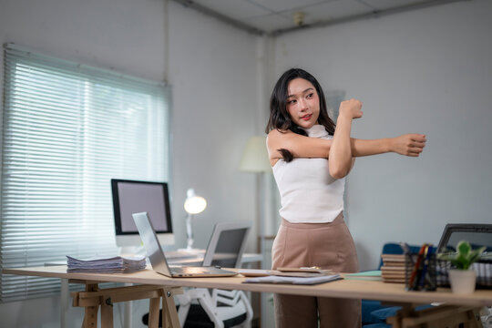 Office worker stretching arms at her desk in the office