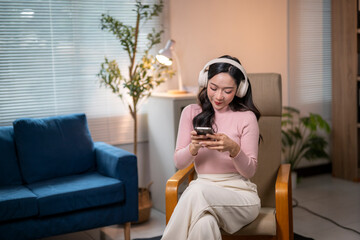 Young woman listening music with headphones and using smartphone at home