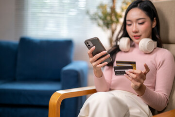 Young woman shopping online using smartphone and credit card at home