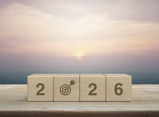 2026 letter with goal flat icon on wood block cubes on wooden table over city tower and skyscraper at sunset, vintage style, Happy new year 2026 success concept