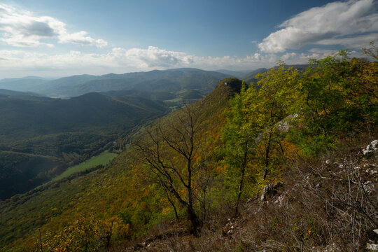 Aerial view of the rugged, forested terrain under a blue sky dappled with white clouds, a serene vista from a high vantage point, Muranska Planina, Banska Bystrica Region, Slovakia.