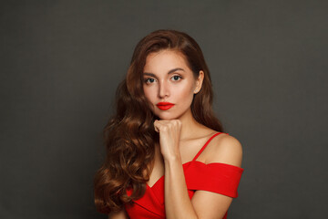 Serious woman with long hair and make-up on black background. Gorgeous woman with curly hairstyle