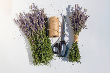 The process of creating lavender bouquets with scissors and jute twine on white