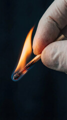 Igniting flame on matchstick held by gloved hand in dramatic dark background