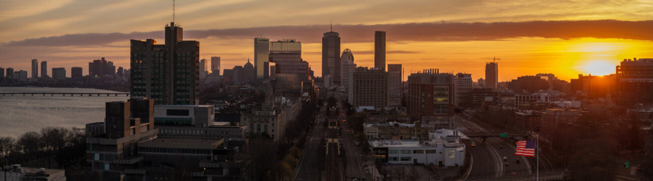 Aerial view of a radiant sunrise casting an orange glow over the Boston skyline, illuminating the John Hancock Tower and Prudential Center, Boston, Massachusetts, United States.