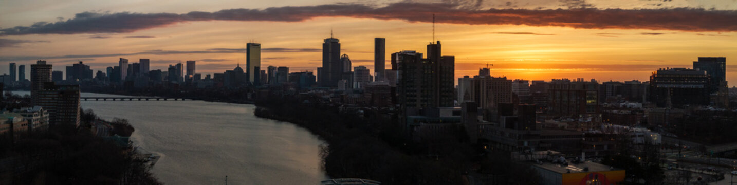Aerial view of the Charles River reflecting the soft glow of sunset against the silhouetted Boston skyline, featuring the Hancock and Prudential towers, Boston, Massachusetts, United States.