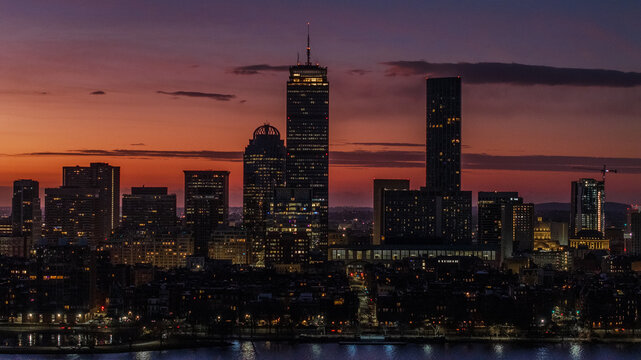 Aerial view of a skyline ablaze with the fading embers of sunset, silhouetting iconic skyscrapers like the Prudential Center against the twilight hues, Boston, Massachusetts, United States.