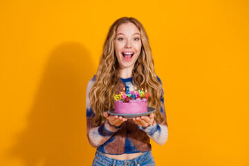 Young woman with pink birthday cake celebrates joy and style in a casual fashion look against a bright yellow background