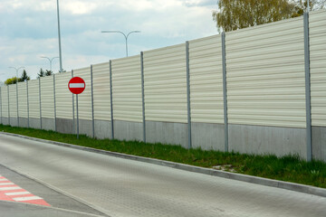A prohibition road sign stands next to the noise barrier