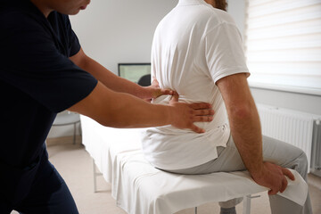 Chiropractor performing manual back adjustment on patient in medical clinic. Physiotherapy, spinal alignment, and rehabilitation treatment for lower back pain relief.