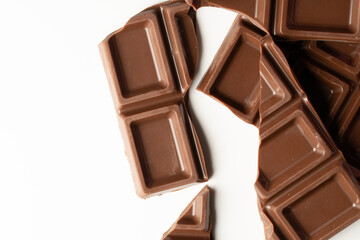 Obraz premium Broken milk chocolate bar pieces on white background