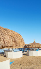 Straw umbrellas, sun loungers and windbreaks on the beach in Hurghada, Egypt.