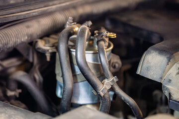 A close-up of a fuel filter and associated hoses in car engine bay. The image focuses on the...
