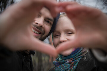 Young Couple Making Heart Shape With Their Hands Outdoors