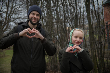 Loving couple making heart sign outdoors together in park