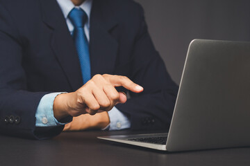 Businessman pointing at laptop computer on office desk.