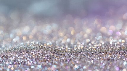 A sparkling silver glitter background with a blurred purple and white bokeh effect in the distance