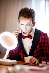 mime puts on makeup in front of the mirror and makes faces