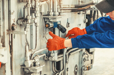 Worker's hands regulate work on heavy equipment. Industrial automation, machine control, background.