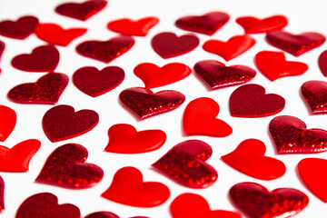 Scattered red heart confetti on white table, symbolizing love, romance, and celebration. Festive background for Valentines Day, wedding, or anniversary.