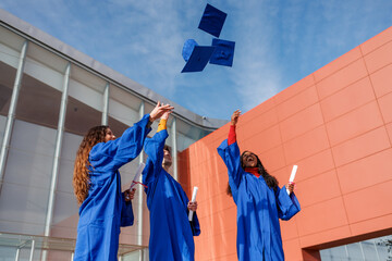 Graduates in blue gowns throwing their caps into the sky, symbolizing achievement and a new beginning