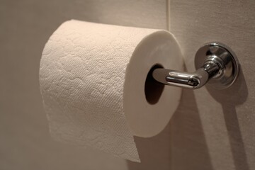 Conceptual image of toilet paper roll put on backwards under roll orientation creating funny bathroom situation.