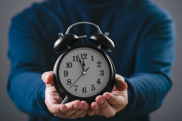 Human hands holding an alarm clock, representing time management, deadline pressure, urgency, productivity, work schedule, punctuality, and efficient planning in modern life.