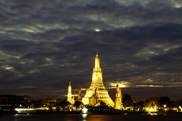 Naklejka premium An abstract, blurred background of nighttime lights along the Chao Phraya River in Bangkok, with Wat Arun, a popular tourist attraction visited by travelers from around the world, in the background.