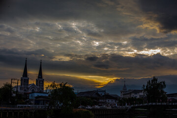 Obraz premium The backdrop of colorful sky lights reflecting off the beautiful river surface at different times of the day, amidst a stunning Christian church in Chanthaburi, Thailand.