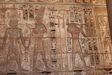 Fototapeta premium Ancient Egyptian wall relief with hieroglyphs and carved figures, archaeological temple art background
