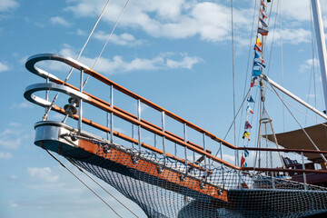 Sailboat deck with ropes and flags of different countries under blue sky in the afternoon